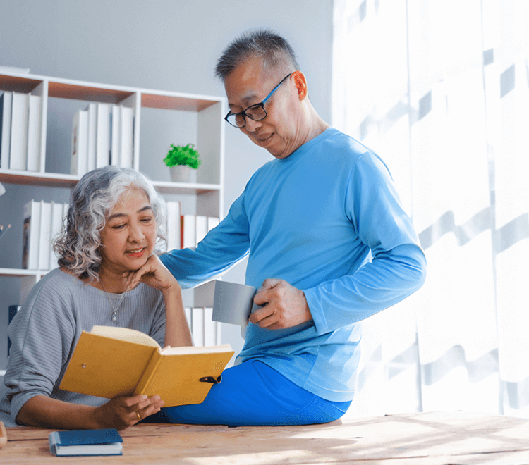 Older asian couple comforts one another at the table.